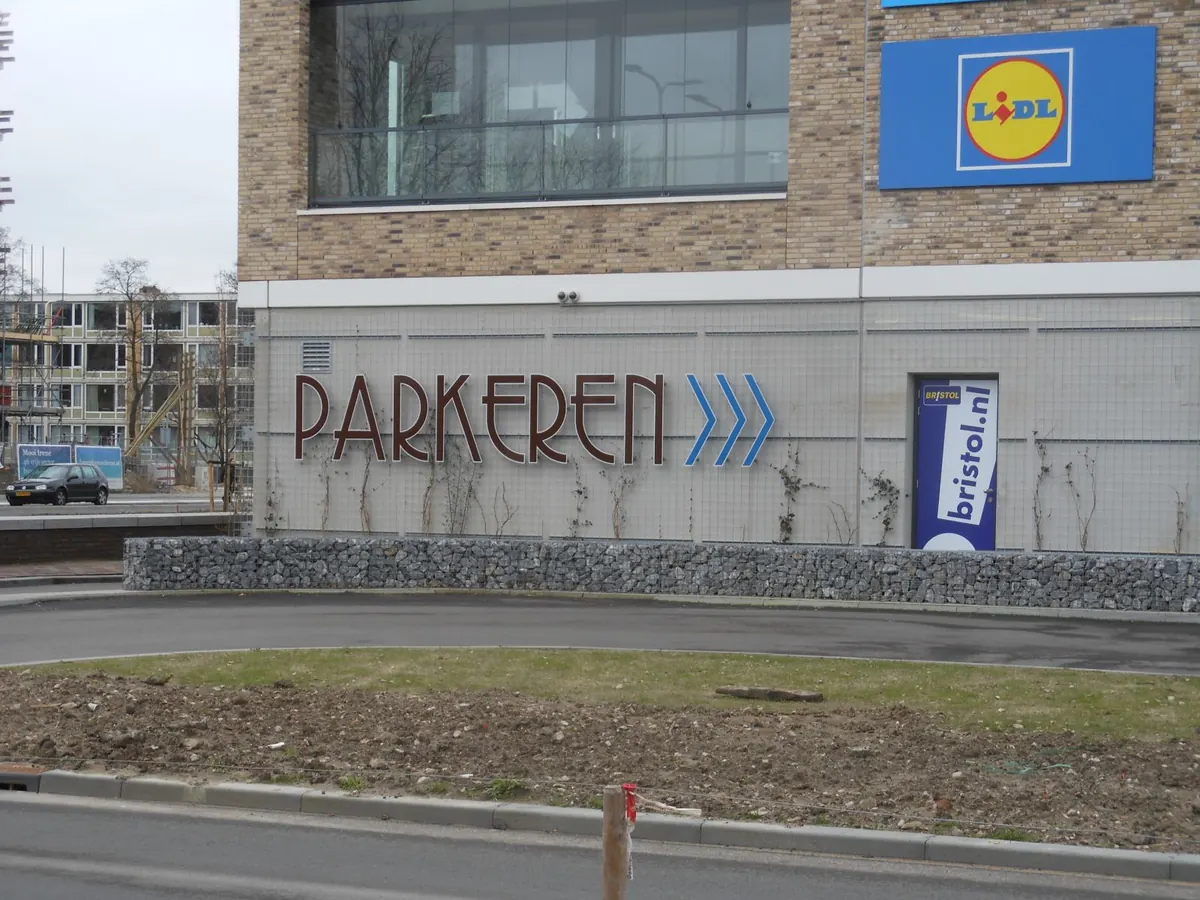 Stalen belettering Parkeren met pijlen op een gevel