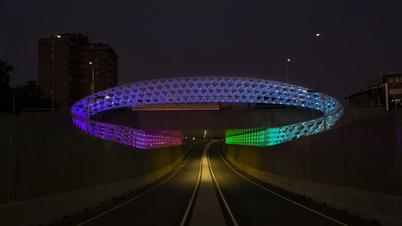 Verlicht ringvormig kunstwerk over een weg in Eindhoven bij nacht